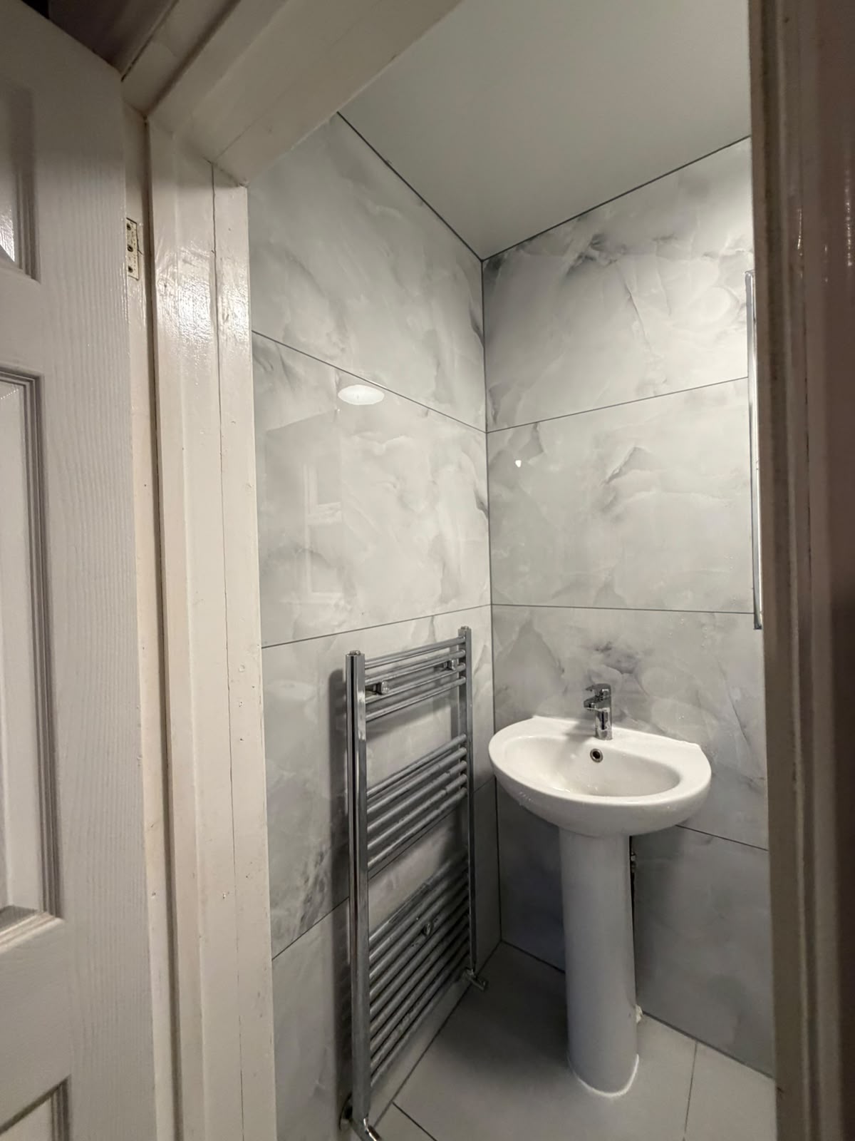 Pedestal basin and towel rail in a marble-tiled bathroom